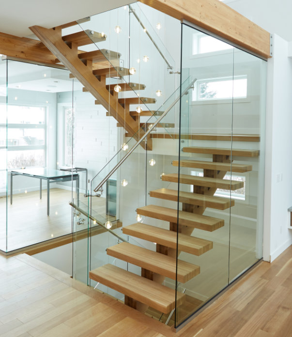 White oak monorail u-shaped staircase with glass panel railing and stainless steel handrail.