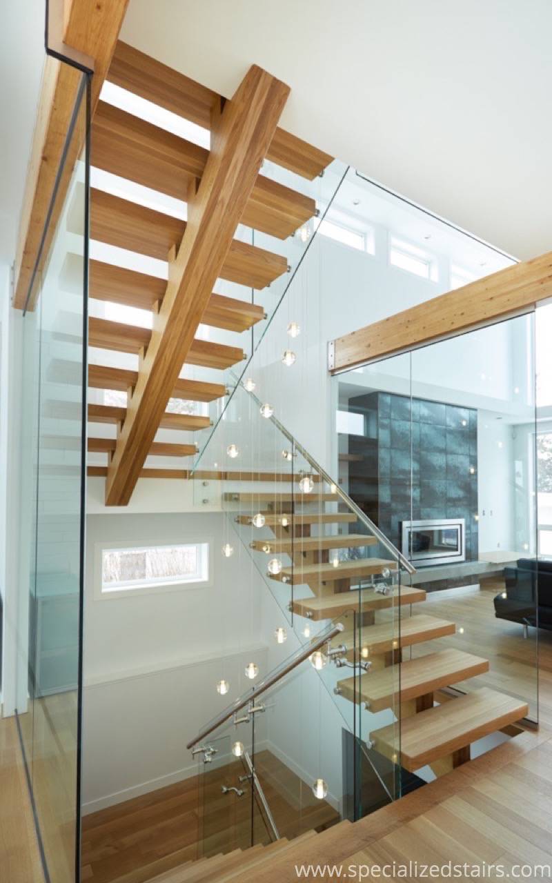 A u-shaped white oak mono stringer staircase with stainless steel handrail and glass railing.