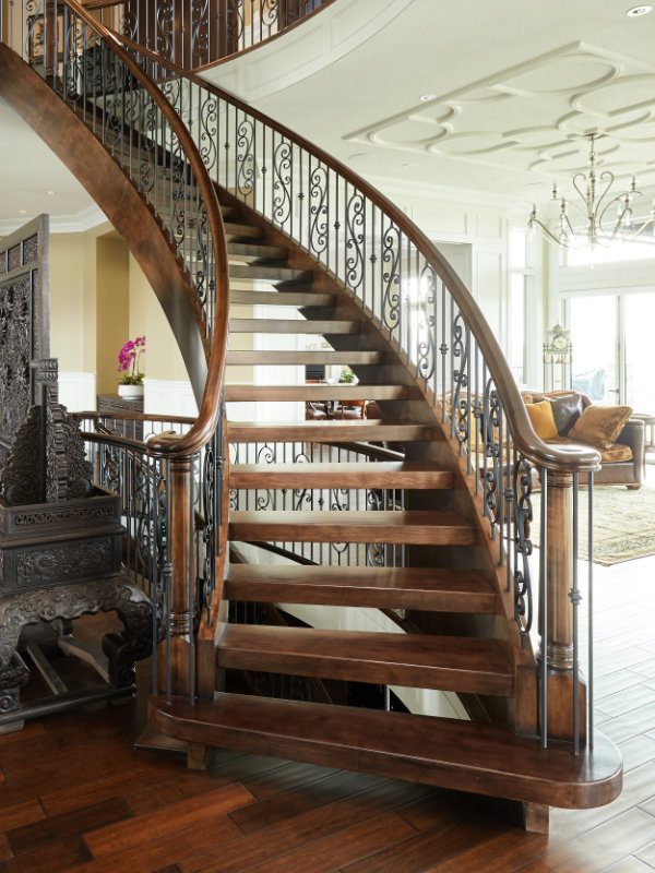 A grand curved staircase with turned posts and traditional scroll style spindles.