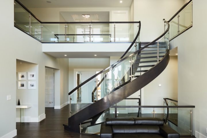 open rise curved staircase with curved clamped glass railing and long balcony railing