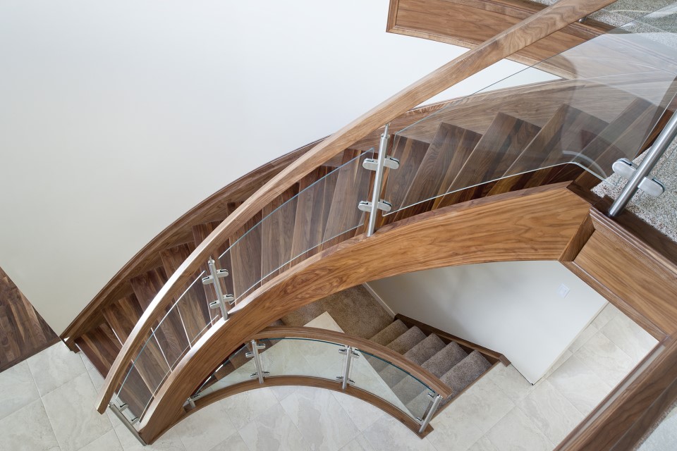 open rise curved walnut staircase with curved clamped glass railing panels and curved walnut handrail